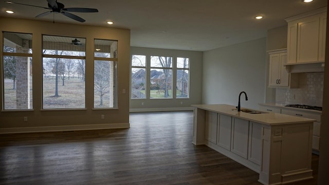 kitchen featuring white cabinetry, sink, dark hardwood / wood-style floors, backsplash, and a kitchen island with sink