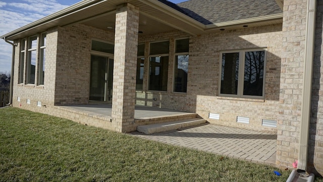 view of exterior entry with a patio area and a yard