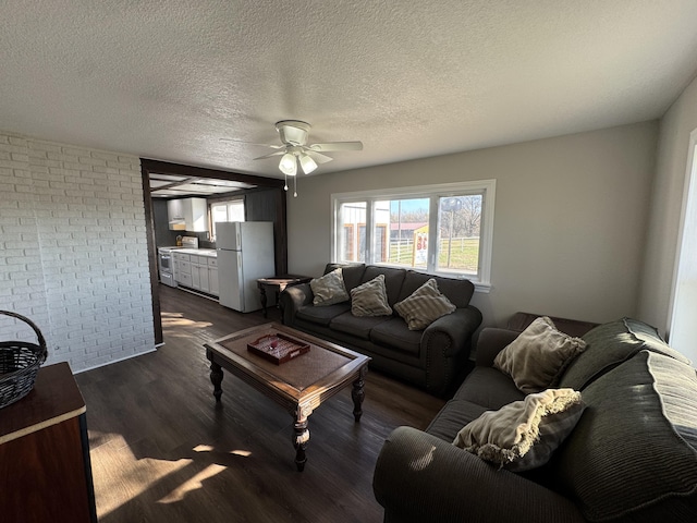 living room featuring a textured ceiling, ceiling fan, dark wood-type flooring, and brick wall