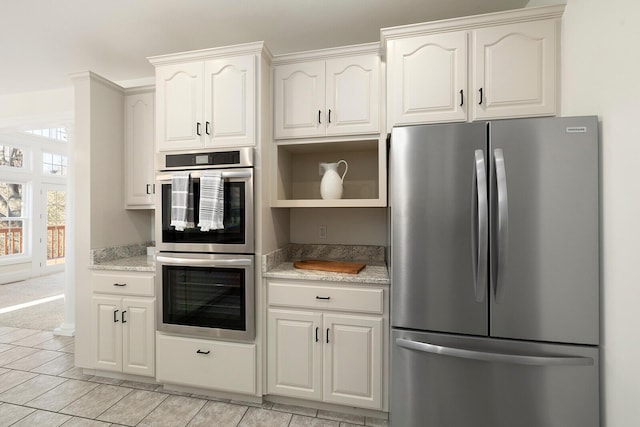 kitchen featuring white cabinets, stainless steel appliances, and light stone countertops