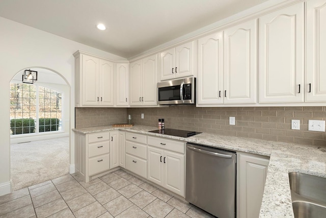 kitchen featuring light stone countertops, light carpet, tasteful backsplash, stainless steel appliances, and white cabinets