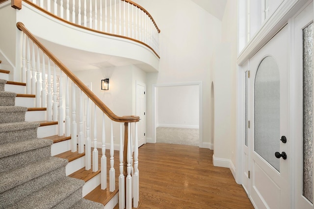 foyer entrance with hardwood / wood-style flooring and a towering ceiling