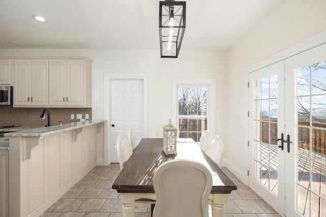 tiled dining room featuring french doors, a healthy amount of sunlight, and sink