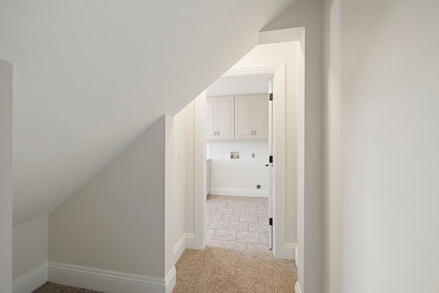 hallway with light colored carpet and vaulted ceiling