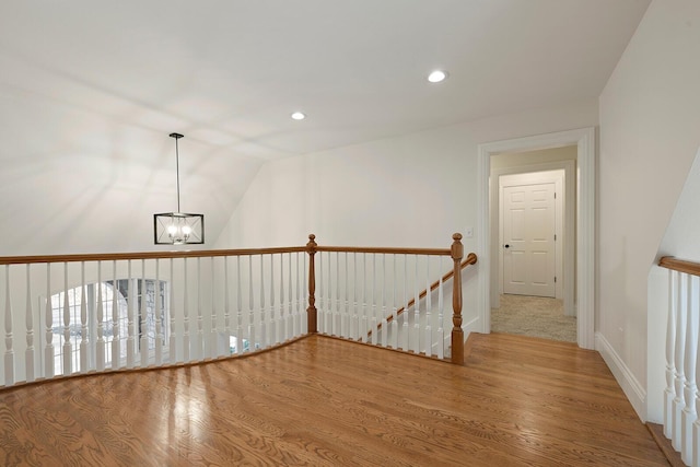 interior space featuring hardwood / wood-style floors, lofted ceiling, and an inviting chandelier