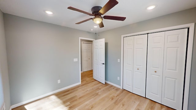 unfurnished bedroom with ceiling fan, light wood-type flooring, and a closet