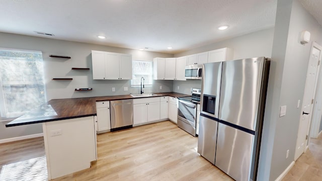 kitchen with white cabinets, light wood-type flooring, sink, and appliances with stainless steel finishes