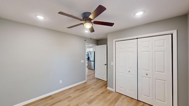 unfurnished bedroom with stainless steel fridge with ice dispenser, a closet, light hardwood / wood-style flooring, and ceiling fan