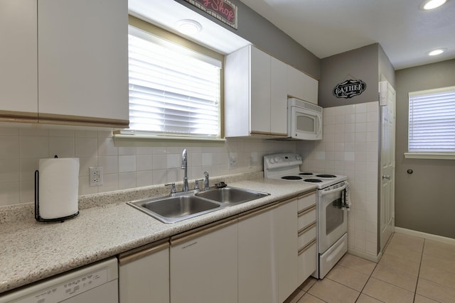 kitchen with light tile patterned floors, white appliances, white cabinetry, and sink