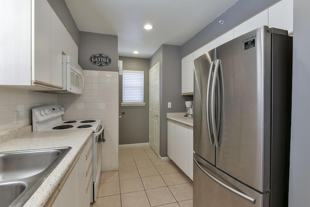 kitchen with light tile patterned floors, white appliances, white cabinetry, and sink