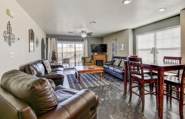 living room with ceiling fan and a textured ceiling