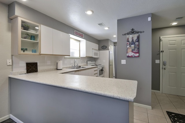 kitchen featuring sink, kitchen peninsula, white appliances, decorative backsplash, and white cabinets