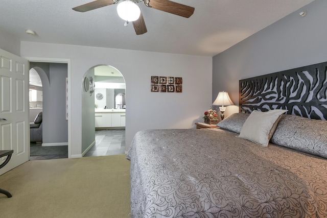 bedroom featuring connected bathroom, ceiling fan, light colored carpet, and a textured ceiling