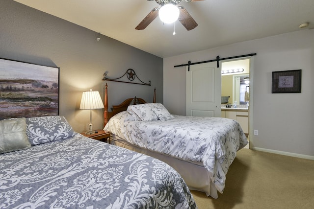 bedroom featuring ceiling fan, a barn door, light carpet, and ensuite bath