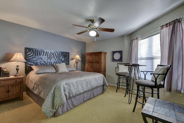 bedroom with a textured ceiling, light colored carpet, and ceiling fan