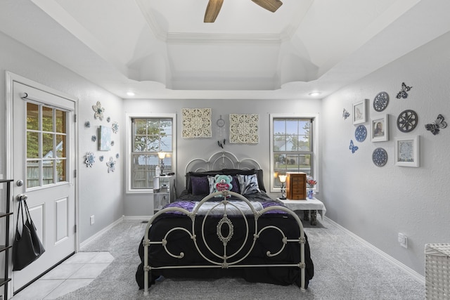 carpeted bedroom with a raised ceiling, multiple windows, and ceiling fan