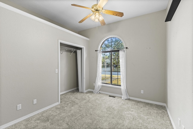 unfurnished bedroom with a closet, light colored carpet, and ceiling fan