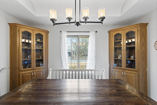 unfurnished dining area featuring vaulted ceiling, an inviting chandelier, and a raised ceiling