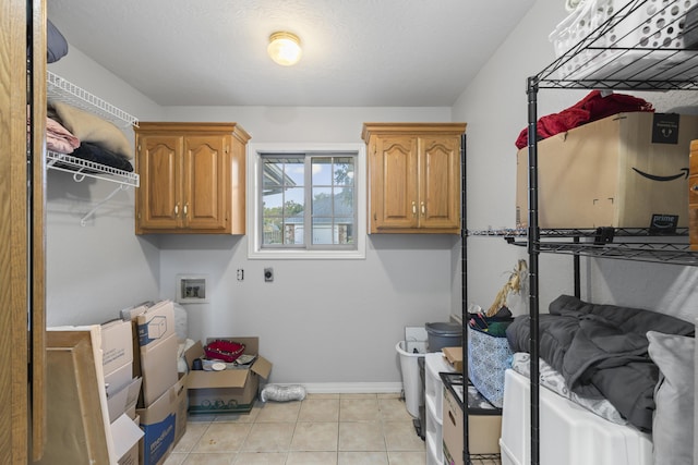 washroom with washer hookup, hookup for an electric dryer, cabinets, and light tile patterned floors