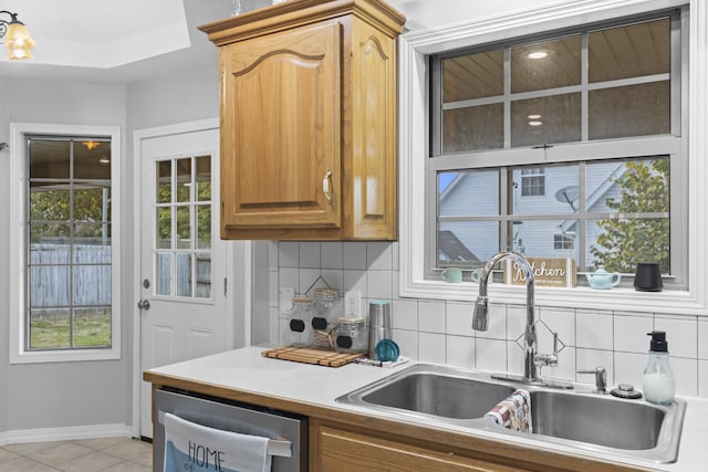 kitchen featuring tasteful backsplash, dishwasher, light tile patterned floors, and sink