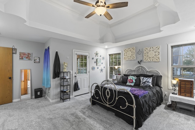 carpeted bedroom featuring ceiling fan, a raised ceiling, and ornamental molding