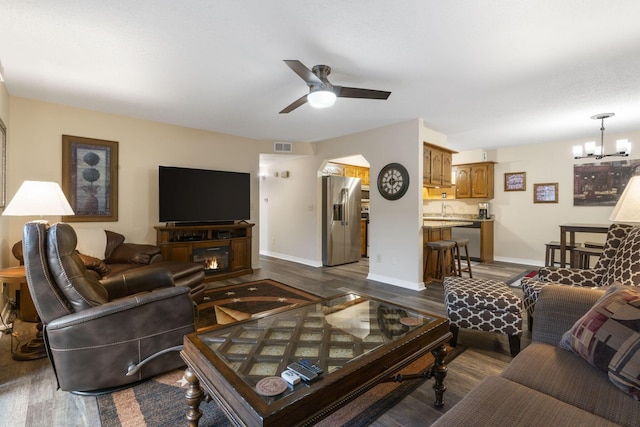 living room with dark hardwood / wood-style flooring, ceiling fan with notable chandelier, and sink