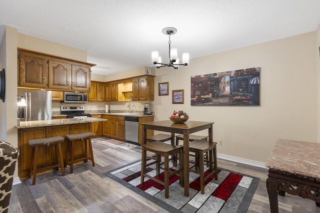 kitchen featuring a kitchen bar, dark wood-type flooring, stainless steel appliances, and an inviting chandelier