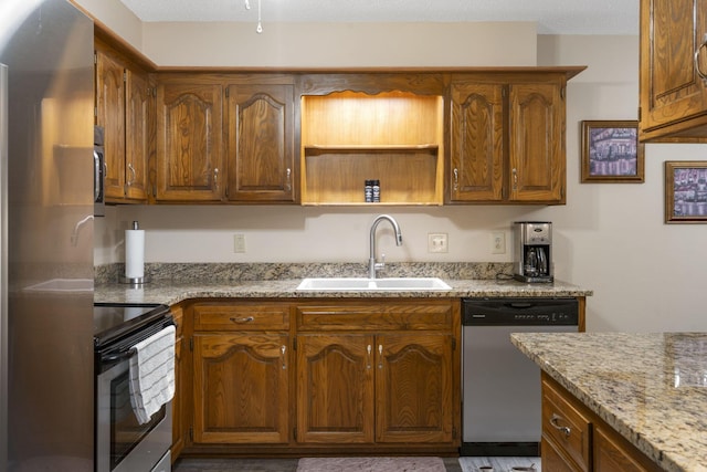 kitchen with a textured ceiling, stainless steel appliances, light stone counters, and sink