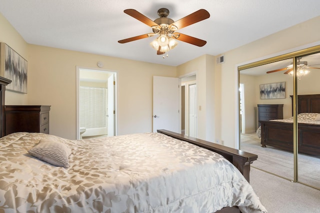 carpeted bedroom featuring a textured ceiling, ceiling fan, ensuite bathroom, and a closet