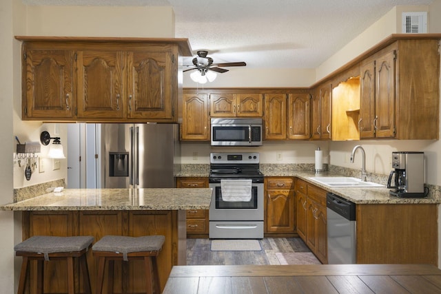 kitchen with sink, a kitchen breakfast bar, kitchen peninsula, light hardwood / wood-style floors, and appliances with stainless steel finishes