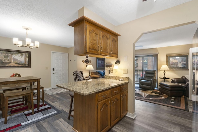 kitchen with dark hardwood / wood-style flooring, kitchen peninsula, a textured ceiling, and hanging light fixtures