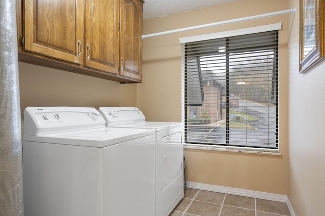 washroom featuring cabinets, a textured ceiling, washing machine and dryer, and light tile patterned flooring