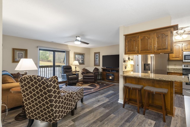 living room featuring ceiling fan and dark wood-type flooring