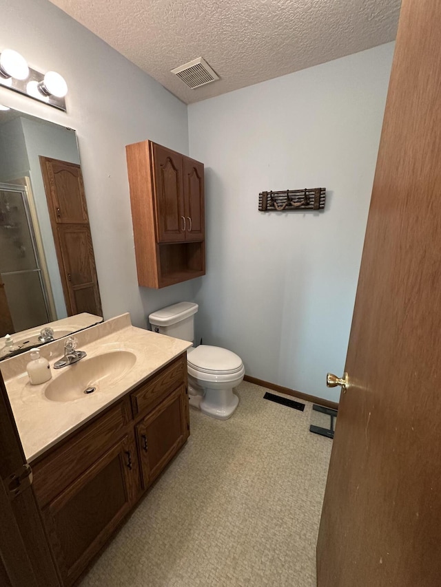 bathroom with vanity, an enclosed shower, a textured ceiling, and toilet