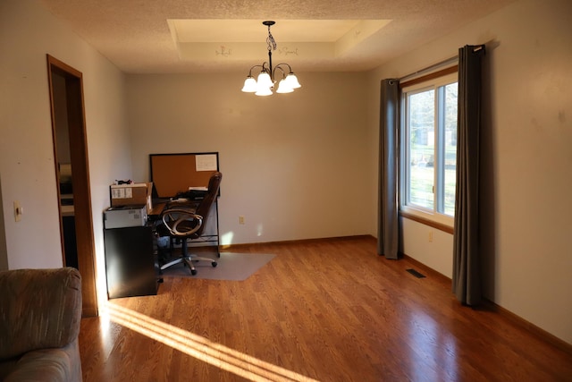 office with hardwood / wood-style flooring, a textured ceiling, a tray ceiling, and an inviting chandelier