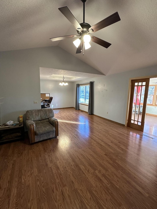 living room with ceiling fan with notable chandelier, hardwood / wood-style floors, a textured ceiling, and lofted ceiling