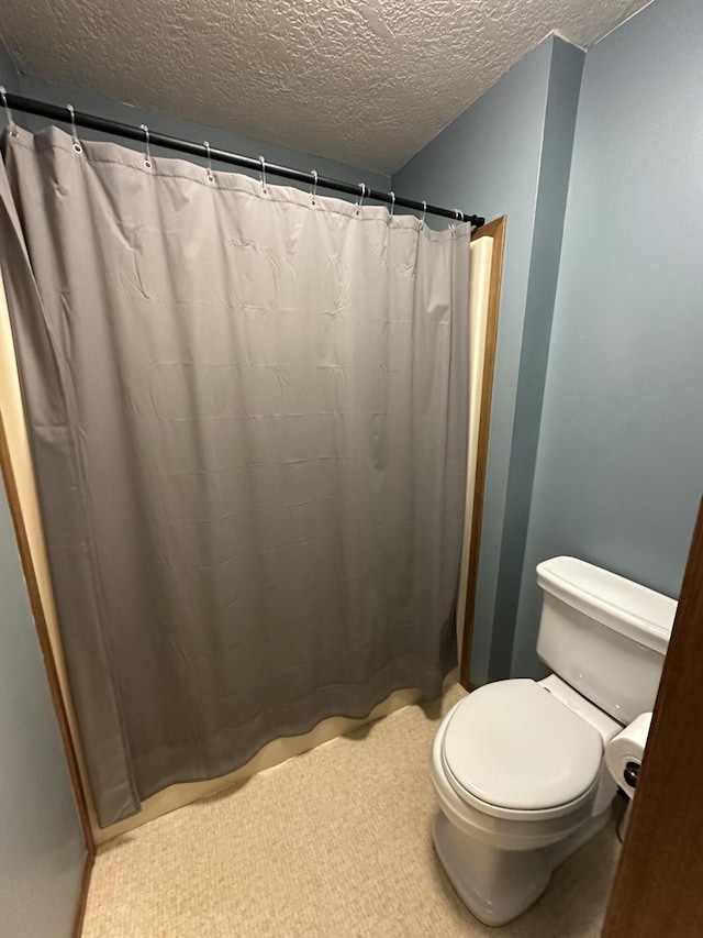 bathroom featuring a textured ceiling, toilet, and walk in shower