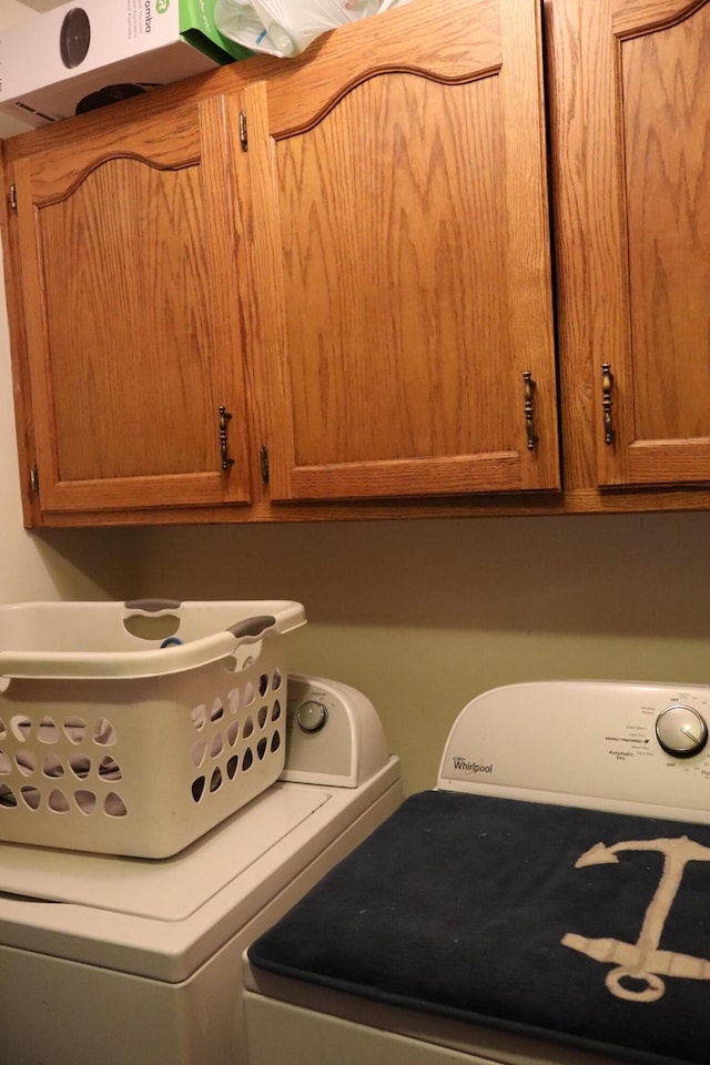 washroom with washing machine and clothes dryer and cabinets