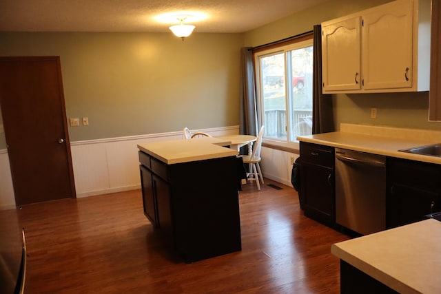 kitchen featuring dishwasher, dark hardwood / wood-style floors, a textured ceiling, a kitchen island, and white cabinetry