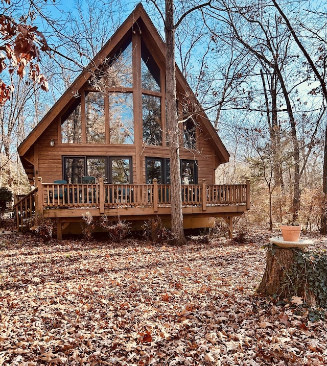 rear view of property featuring a sunroom and a wooden deck