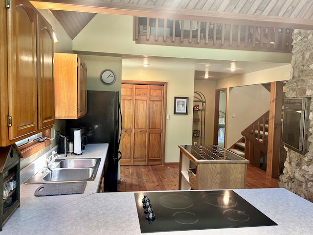 kitchen with wooden ceiling, lofted ceiling, black appliances, sink, and light hardwood / wood-style flooring