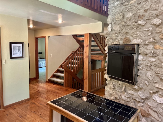 kitchen featuring hardwood / wood-style floors, tile countertops, and oven