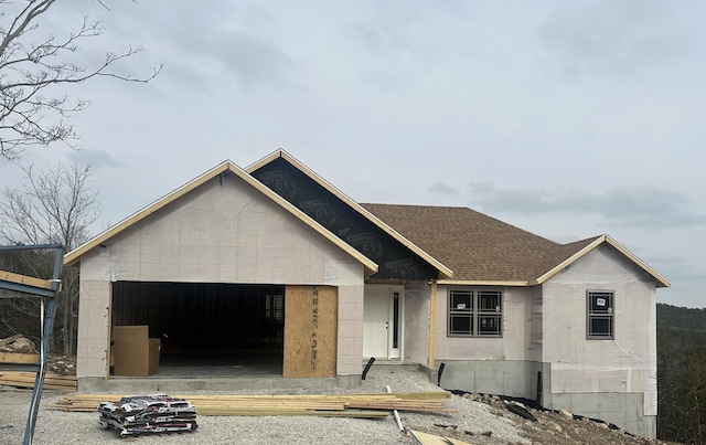 property in mid-construction featuring a garage, roof with shingles, and concrete block siding