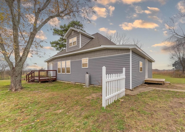 property exterior at dusk featuring a deck and a yard