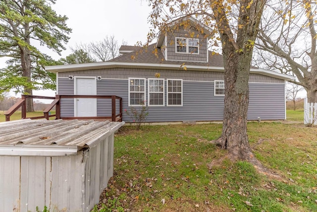 back of property featuring a wooden deck and a yard