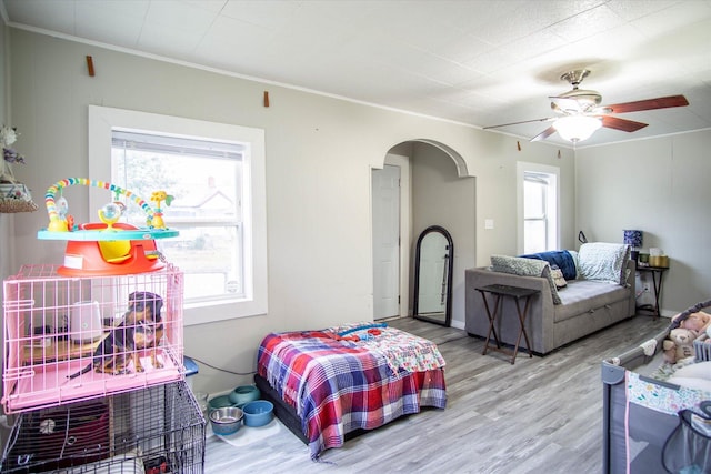 bedroom with wood-type flooring, ornamental molding, and ceiling fan