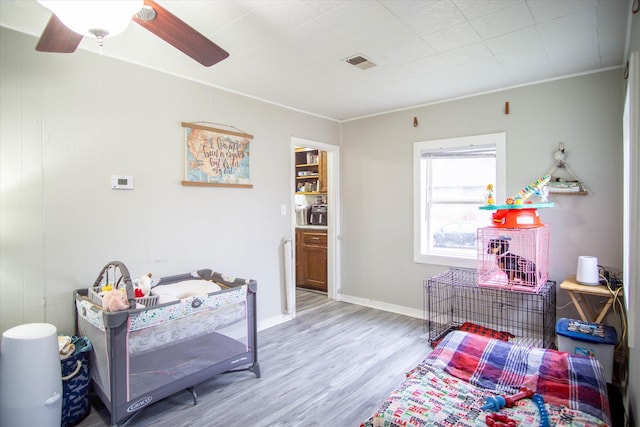 bedroom featuring ornamental molding, ceiling fan, and light wood-type flooring