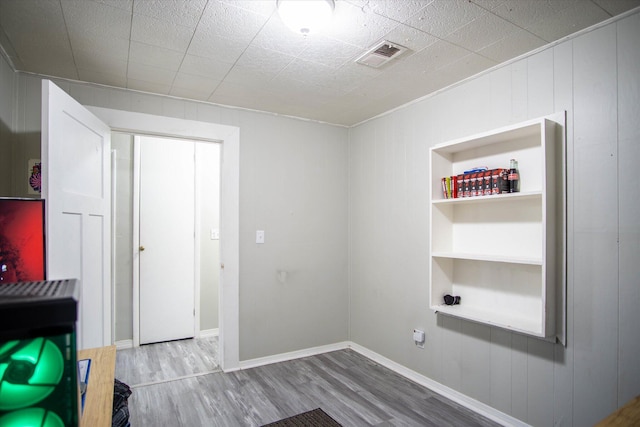 interior space with built in shelves and wood-type flooring