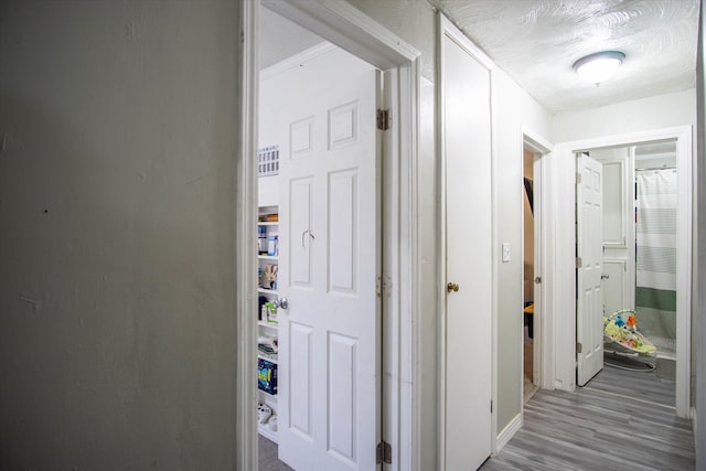 corridor featuring a textured ceiling and light wood-type flooring