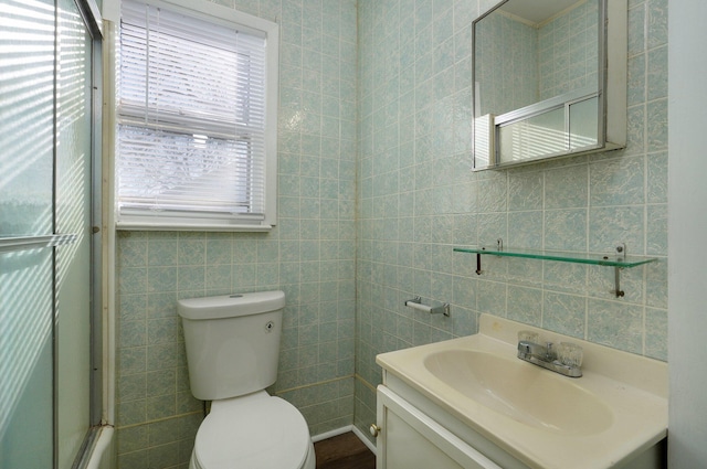 full bathroom featuring vanity, toilet, tile walls, and bath / shower combo with glass door